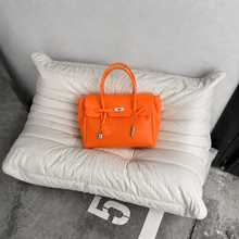 Orange Sencieres jelly Firkin bag, glossy translucent TPU handbag — angled side view